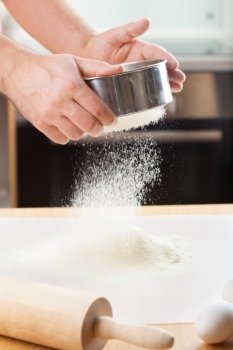 mans hands sifting flour through a sieve for baking 