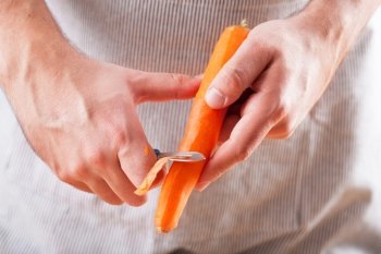 man hands peeling carrot