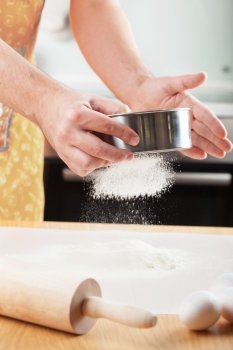 mans hands sifting flour through a sieve for baking 