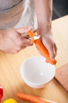man peeling carrot in kitchen 