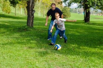 Young boy playing football with his father outdoors
