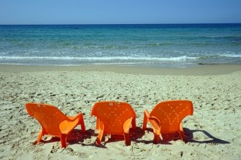 Orange plastic chairs on the sand beach near Netanya, Israel