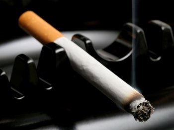 Burning cigarette resting on ashtray 