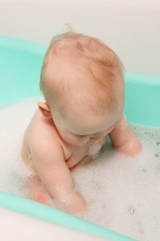amusing little baby attentively takes a bath. little baby takes a bath