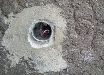 Concrete wall with exposed wires in wall socket 