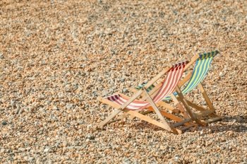 two deckchairs on a pebbled beach in summer