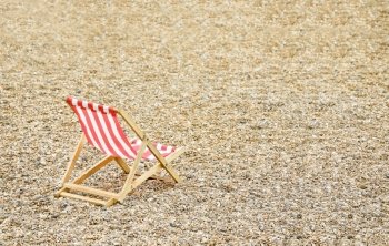 single wooden deck chair on a deserted pebbled beach
