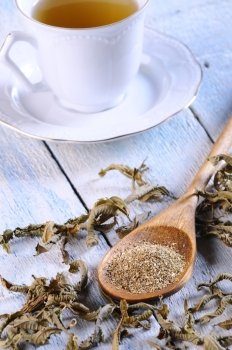 Cup of chamomile and herbs on wooden table in the kitchen.