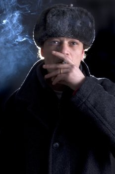 A man, dressed in a 70’s Soviet outfit, smoking a cigarette