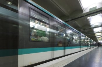 An accelerating metro underground carriage, leaving the platform. The motion blur together with the reflection and the commuters leaving the station create a very dynamic feel of travelling