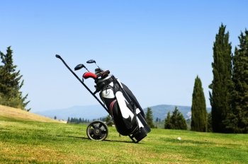 Golf bag with several clubs on a trolley on the fairway of a golf course