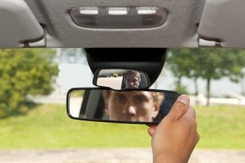 Man, adjusting the rear view mirror of his car