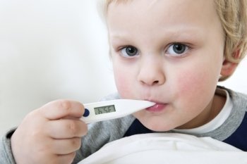 Portrait of a young child with a thermometer in his mouth measuring his fever