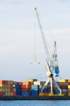 Harbor crane, surrounded by containers in the evening light