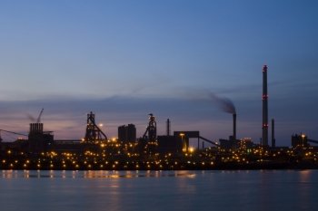 Steelworks at dawn, seen from across a sluice entrance. An industrial, almost silhouette view of heavy industry.