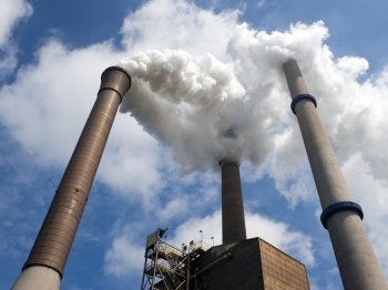 Three smoke stacks, emitting steam, with a centered and vertical vanishing point