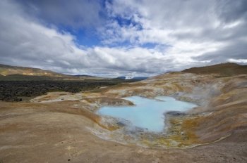 A turquoise lake in a caldera of the Krafla volcanic system, with the lava fields and geothermal activity and its mudpools in the Myvatn region, Iceland