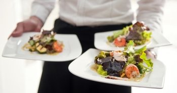 Waiter, carrying three plates with a rich salad 