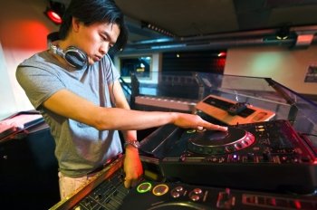 DJ working on the faders and turntables during his act in a club