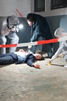 Murder scene with two forensic analysts and a police lieutenant investigating a crime on a businessman in a basement