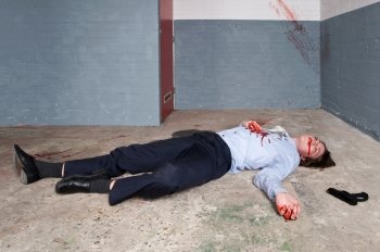 Murdered businessman lying on the floor of a basement, the gun next to the dead body