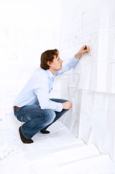 Industrial design engineer calculating measurements and tolerances on a technical drawing using a calculator