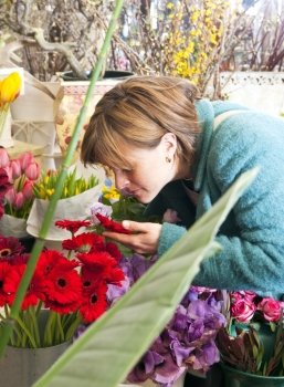 Woman absorbing the scent of a flower whilst shopping at a florist