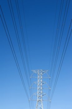 High voltage power pole against blue sky