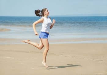 Attractive young woman running alone on the beach