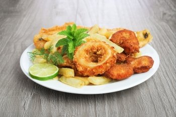 Seafood dish with crumbed fish,calamari,prawn and potato chips on vintage table