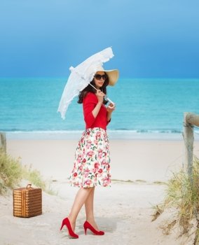 beautiful lady in red traveler in retro style dress  on the beach