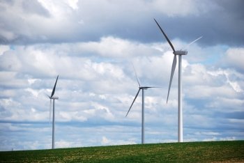 Three wind turbines on a blue and cloudy sky. Sustainable energy.. Three wind turbines