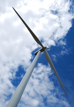 Wind turbine on blue and cloudy sky in vertical view. Wind turbine on cloudy sky