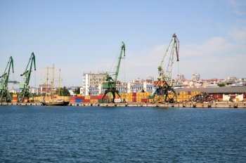 Overview of stacked containers and cranes at harbour