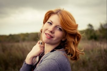 Portrait of a beautiful redhair girl in the autumn park. Caucasian race.