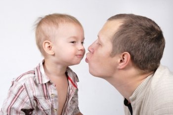 Daddy kisses his little son on the white background
