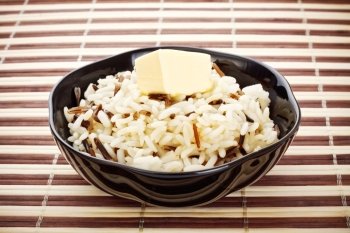 black bowl with cooked rice and butter on bamboo napkin