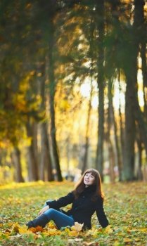 beautiful girl sitting on grass in autumn park