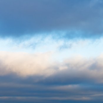 gray winter cloud layers in blue afternoon sky