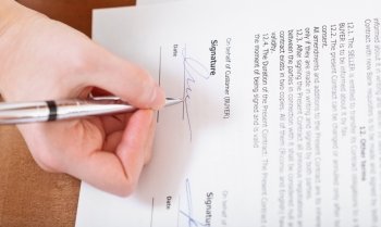 buyer signs a contract by silver pen on table