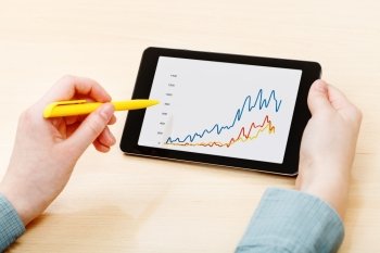 businessman touches by pen of tablet PC with graph on screen at office table
