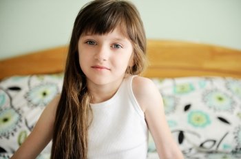 Portrait of little girl sitting in bed in early morning