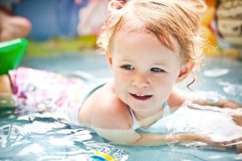 Little blondie girl in the swimming pool, soft focus
