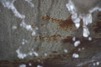 Close up of water dripping from a rusted fountain bowl