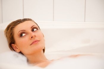 Young beautiful girl is relaxing in a bathtub with foam 