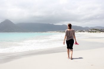 Woman walking along the Beach of Kommetjie with an upcoming storm in the background