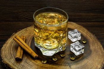 Alcoholic beverage with cinnamon and ice on a wooden background.