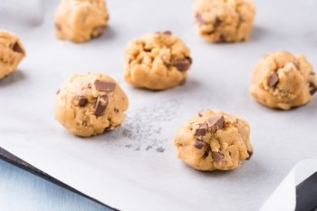 Raw cookie dough on a baking tray with parchment paper, selective focus