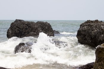 Beautiful waves of a beach of Goa, India. Wave crashing on the rocky reef.