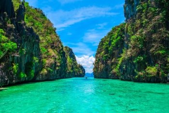 Tropical landscape with rock islands, lonely boat and crystal clear water, El Nido, Palawan, Philippines